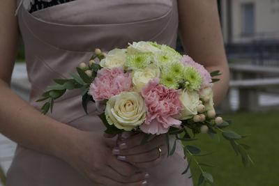 Midsection of bride holding rose bouquet