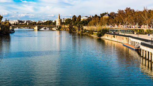 Bridge over river in city against sky