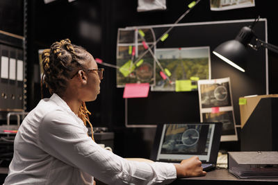 Side view of man using laptop at office