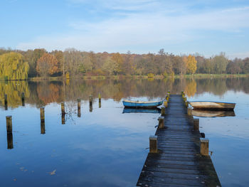 Wooden posts in lake against sky during autumn