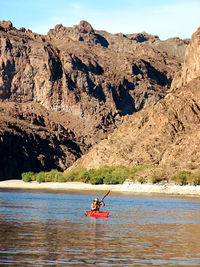 Man rowing boat on rock in water