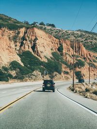 Vehicle moving on road against mountains