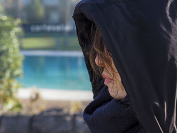 Close-up of woman wearing hoodie sitting outdoors