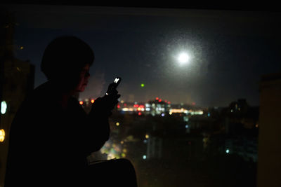 Side view of man using mobile phone at night