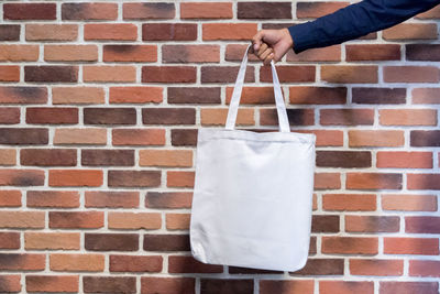 Midsection of person holding ice cream against brick wall