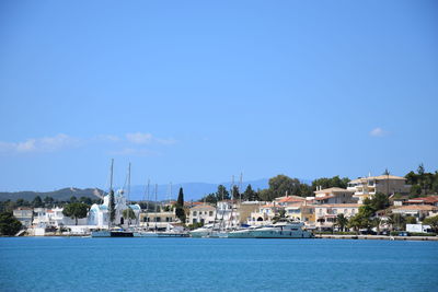 View of townscape by sea against blue sky