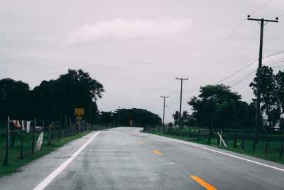 Road by trees against sky