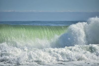Waves splashing on sea against sky