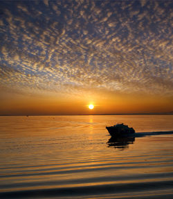 Silhouette boat in sea against sky during sunset