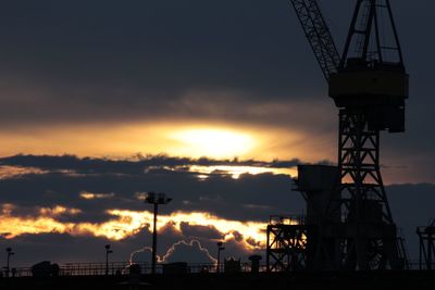 Low angle view of silhouette cranes against sky during sunset