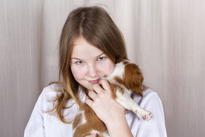 Portrait of smiling girl holding puppy at home