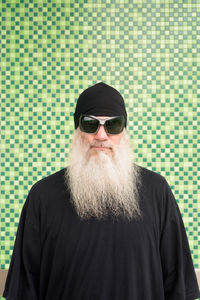 Portrait of man wearing sunglasses standing against wall