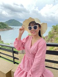 Woman wearing sunglasses standing against pink water