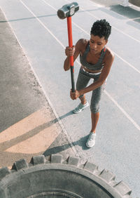 High angle view of woman hammering tire on road