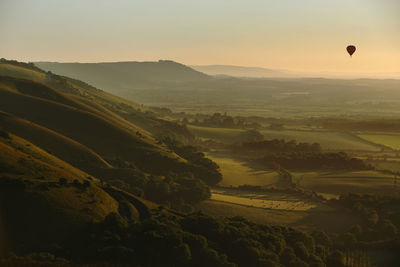 Hot air balloon flies at sunset over devil's dyke in the south downs near brighton east sussex, uk