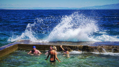 People enjoying in sea against sky