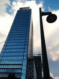 Low angle view of modern building against cloudy sky