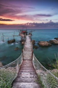 Pier over sea against sky during sunset