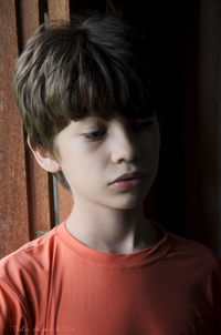 Portrait of a boy at the window wearing orange shirt. 