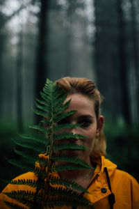 Portrait of young woman against plants in forest