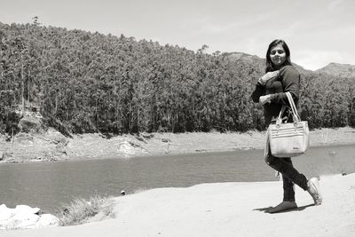 Full length of young woman standing by river