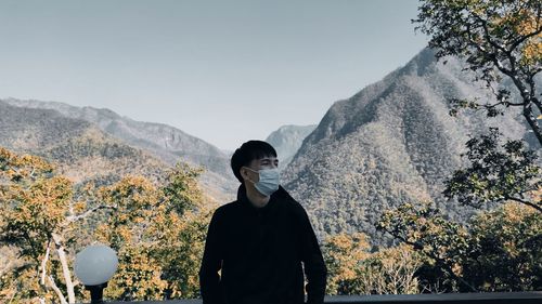 Rear view of man standing on mountain against sky