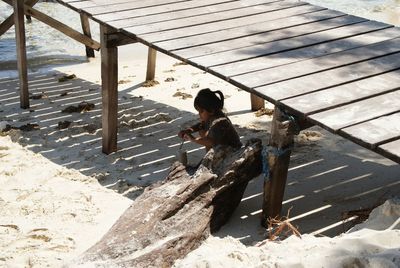 High angle view of woman sitting on bench at beach