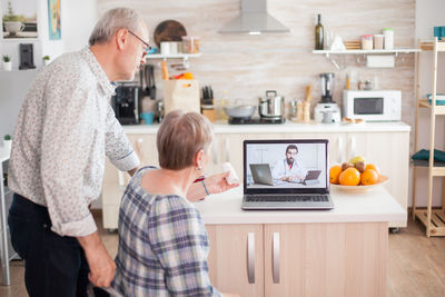 Rear view of man using laptop on table