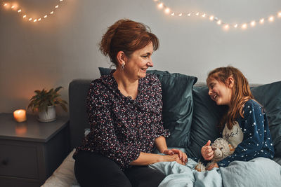 Mother playing with her little daughter in bed, having fun before going sleep