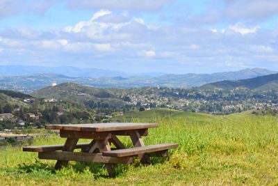 Bench on landscape against sky