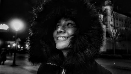 Smiling woman in fur coat at night