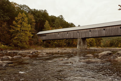 Bridge over river in forest against sky