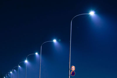 Low angle view of street lights against blue sky