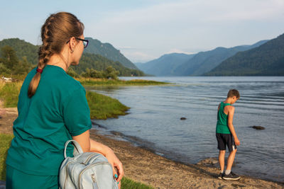 Rear view of friends on lake against mountains