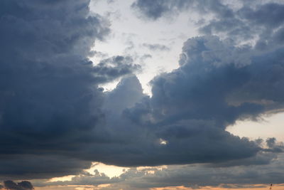 Low angle view of sunlight streaming through clouds