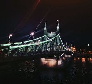 Illuminated bridge over river at night