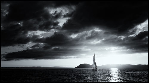 Sailboat in sea against sky during sunset