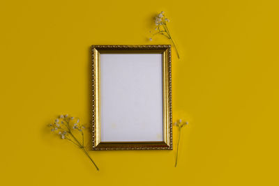 Directly above shot of picture frame on yellow background