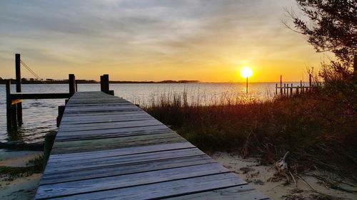 Pier over sea against sky during sunset