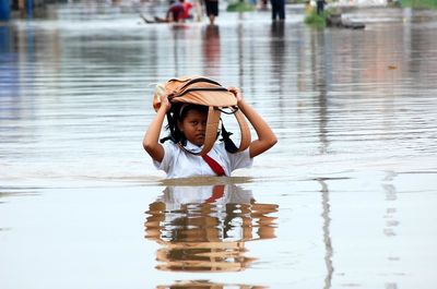 Portrait of girl with bag on head walking in water
