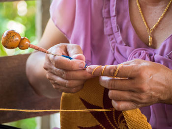 Midsection of woman crocheting while sitting at home