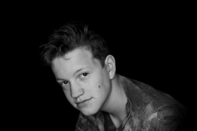 Portrait of a teenage boy against black background