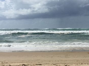 Scenic view of beach against cloudy sky