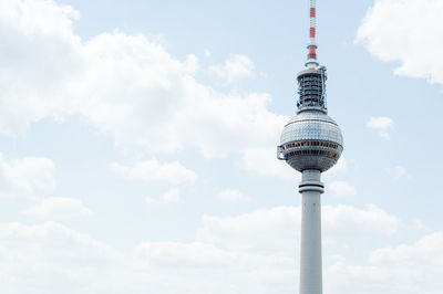 Communications tower in city against sky