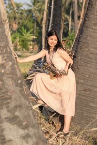 Portrait of beautiful smiling woman standing in the middle of a tree with a saxophone