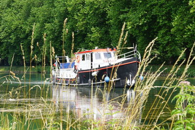 Boats sailing in river by trees in forest