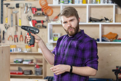 Portrait of man holding camera while standing at store