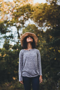 Young woman looking away while standing on tree