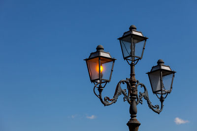 Low angle view of street light against blue sky