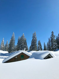 Snow covered landscape against clear blue sky